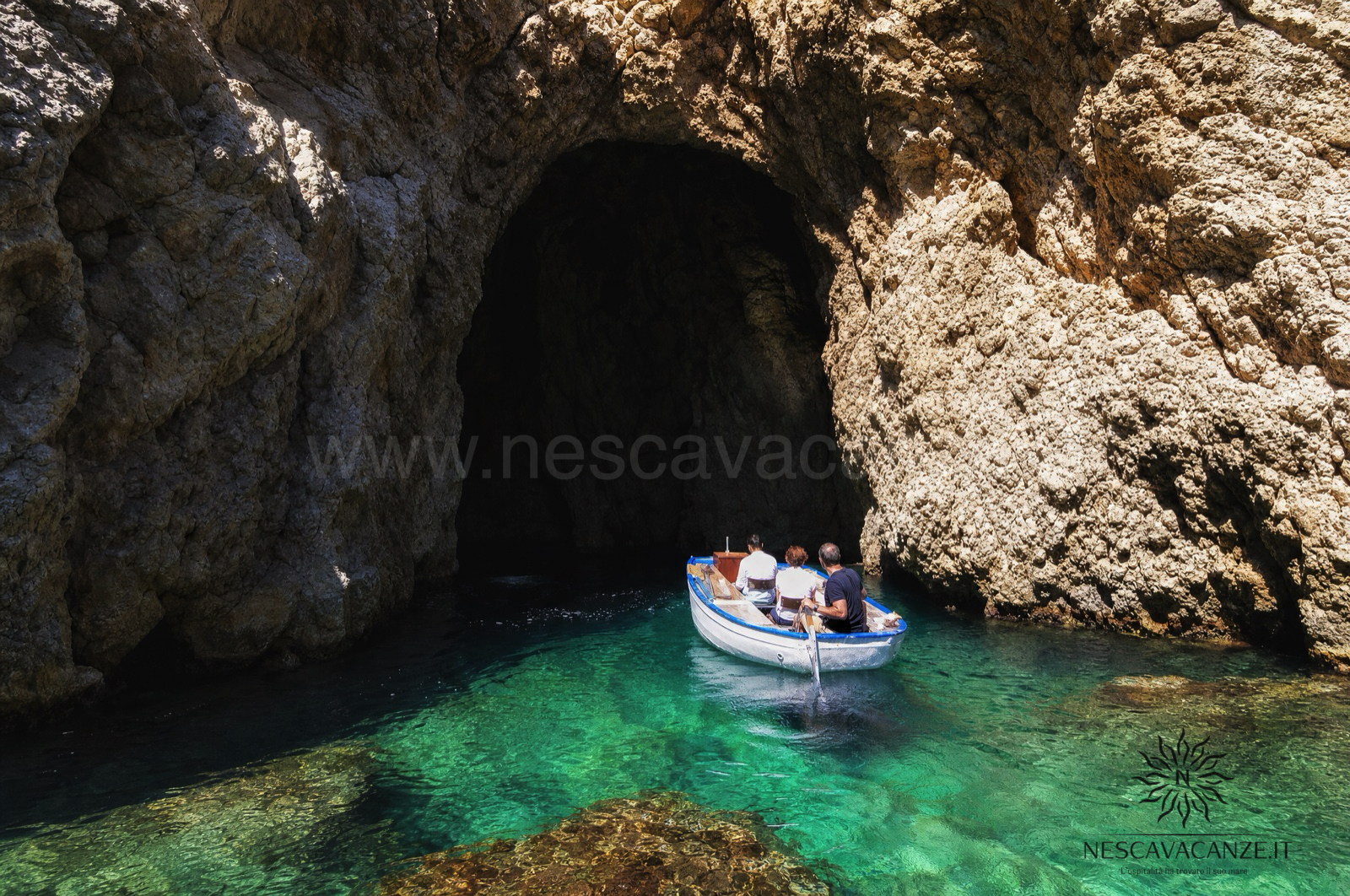 Barca all'ingresso di una grotta marina con acqua turchese lungo la costa adriatica del Salento, vicino a Castro