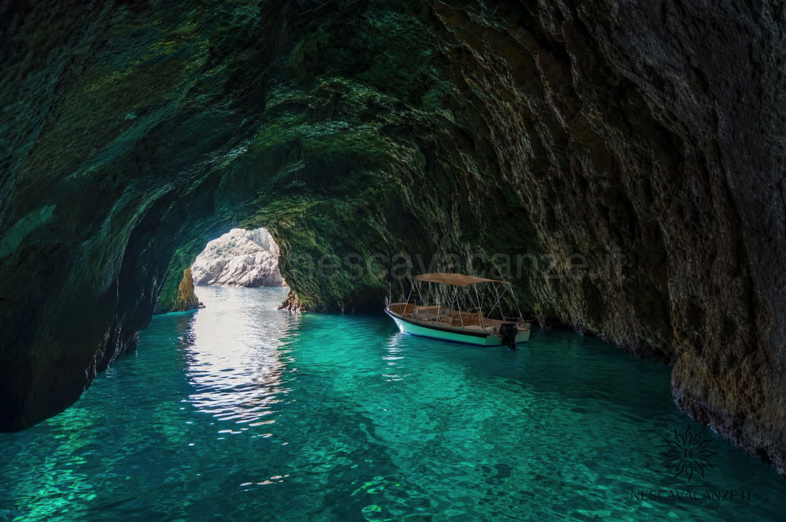 Interno di una grotta marina del Salento con acqua turchese illuminata e una piccola barca, vicino a Santa Maria di Leuca