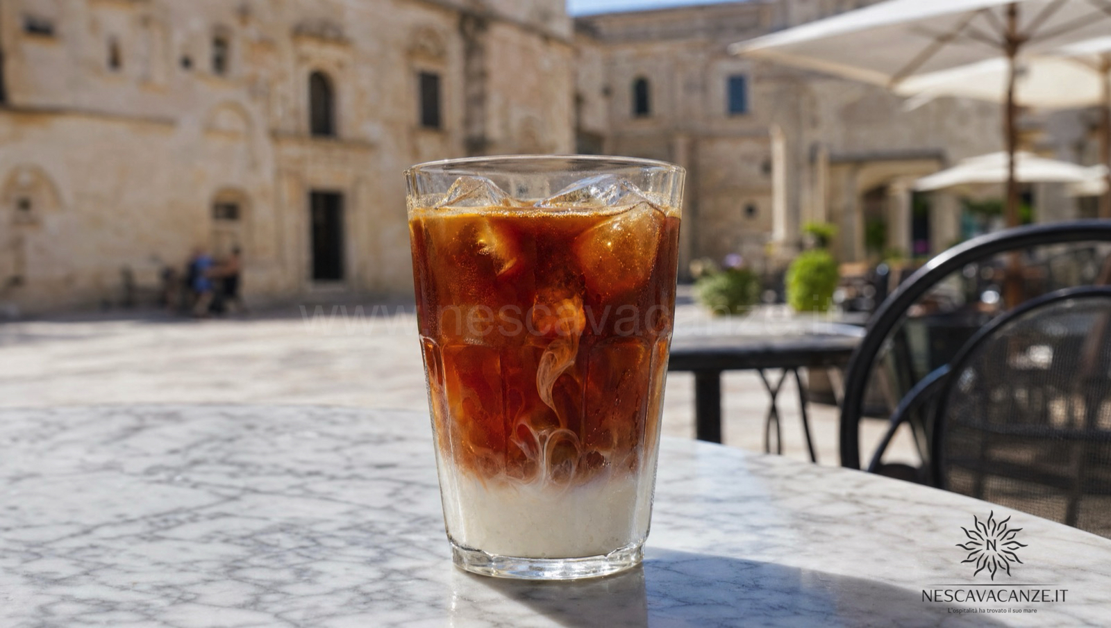 Caffè leccese in ghiaccio: espresso caldo e zuccherato versato su cubetti di ghiaccio con un dito di latte di mandorla, in un bar di una piazza salentina assolata