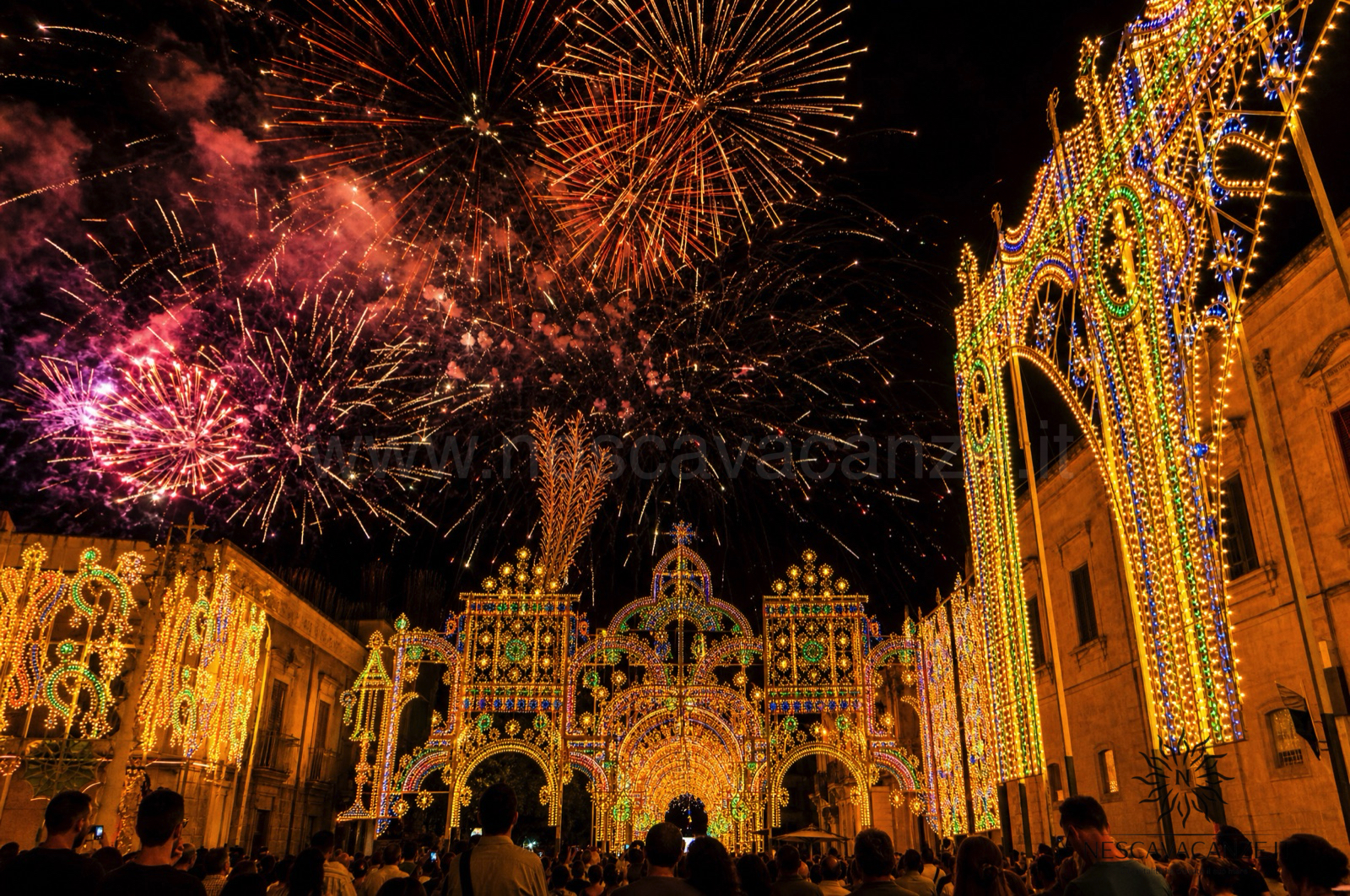 Fuochi d'artificio nel cielo sopra le luminarie accese di una festa patronale salentina, come per San Lorenzo a Barbarano
