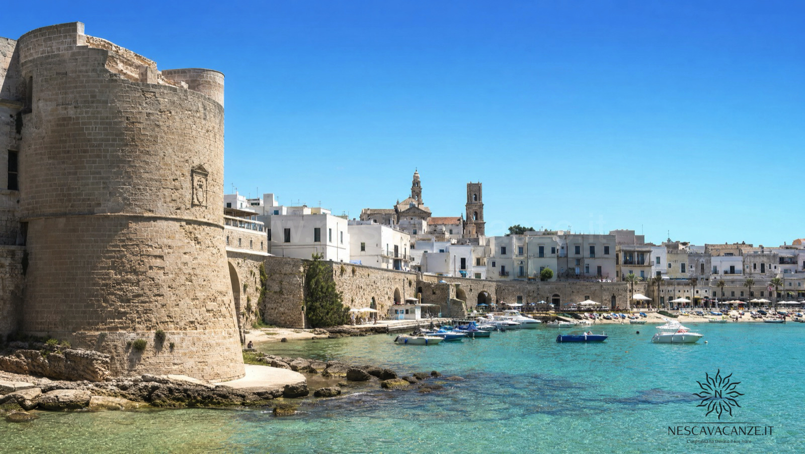 Il centro storico bianco di Otranto con il Castello Aragonese e il porticciolo con le barche affacciati sul mare turchese dell'Adriatico