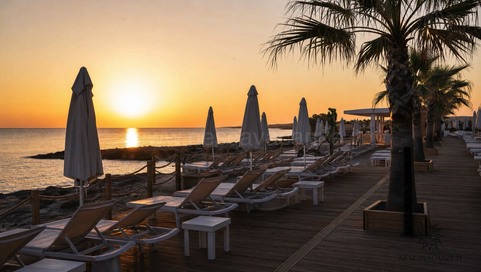 Lettini e ombrelloni di un lido attrezzato sulla costa salentina al tramonto