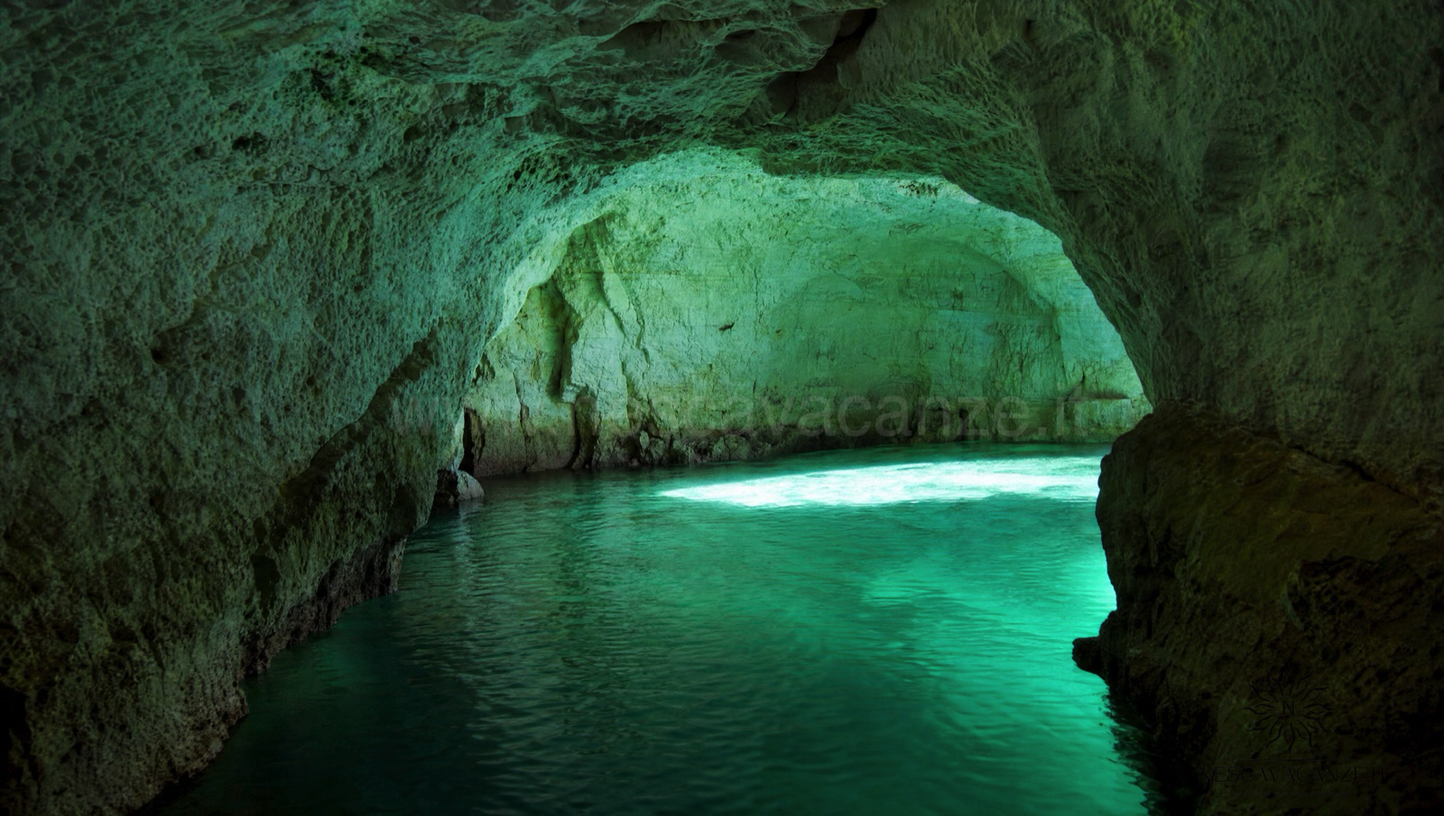 Interno di una grotta marina del Salento con l'acqua color verde smeraldo illuminata dal sole che filtra da un'apertura sottomarina