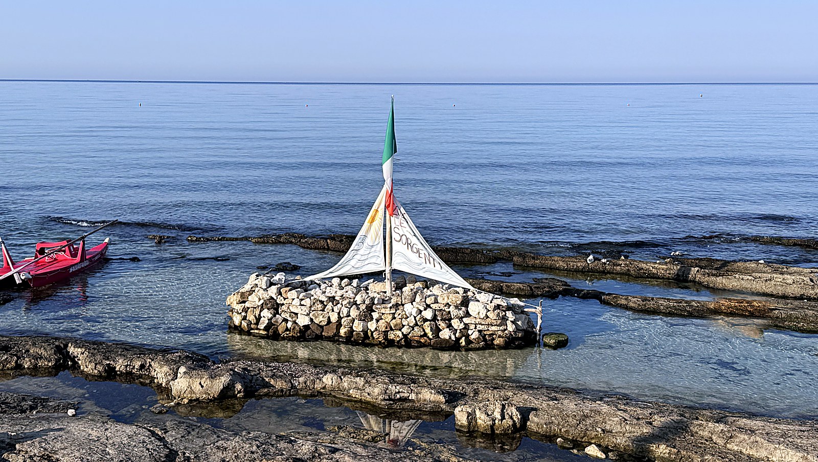 Le Sorgenti di Torre Vado: vasche di acqua bassa separate da cordoli di roccia calcarea, con un gozzo rosso ormeggiato