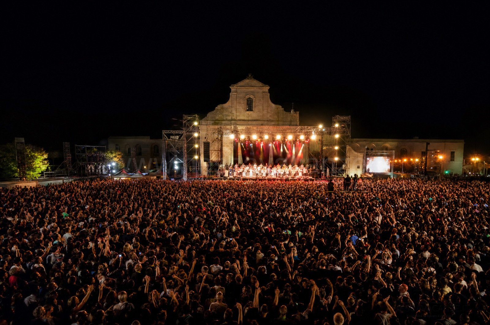 La folla del Concertone della Notte della Taranta a Melpignano di notte davanti al palco illuminato, in Salento