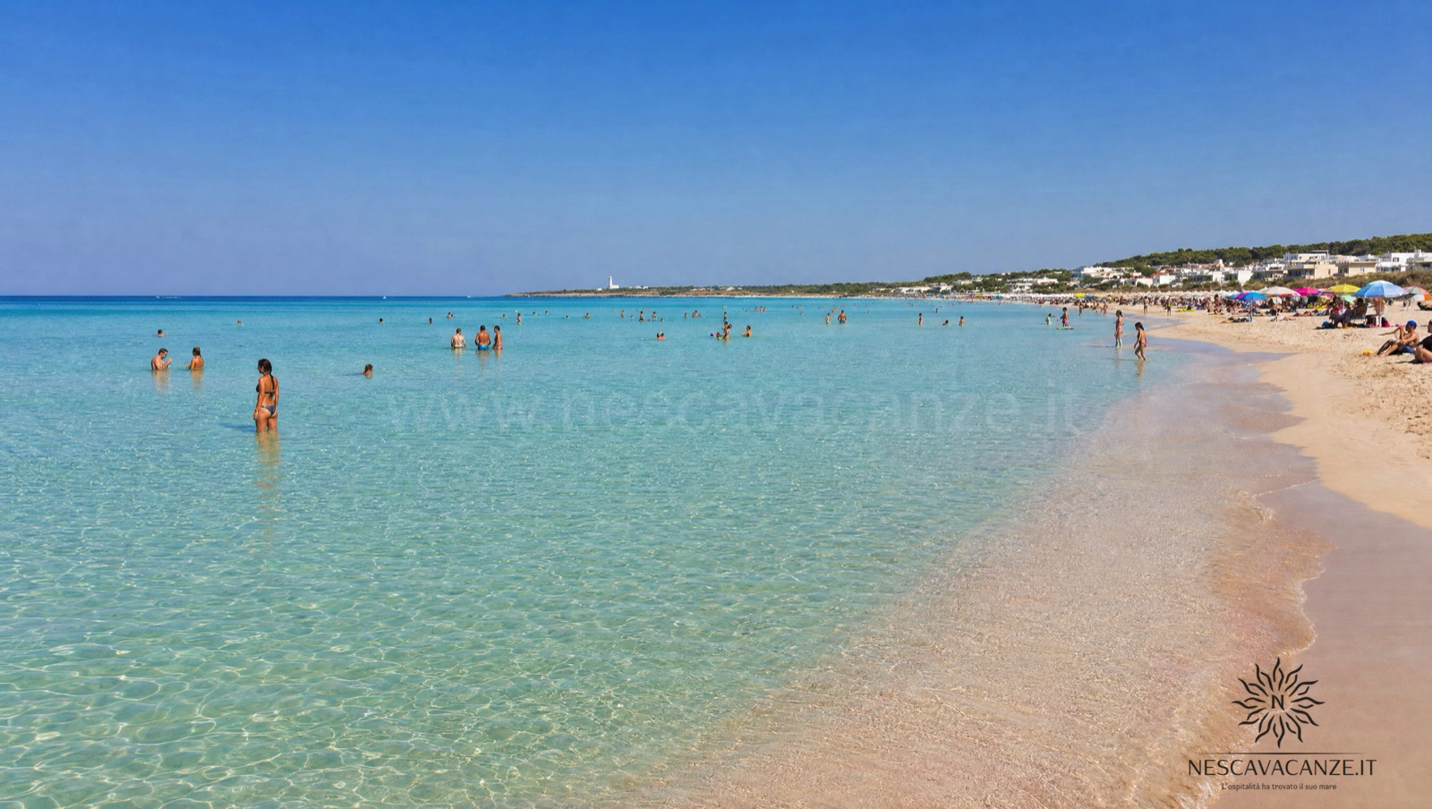 La spiaggia di Pescoluse, le Maldive del Salento, con sabbia bianca finissima e acqua bassa cristallina dal turchese al verde smeraldo, con bagnanti vicino alla riva