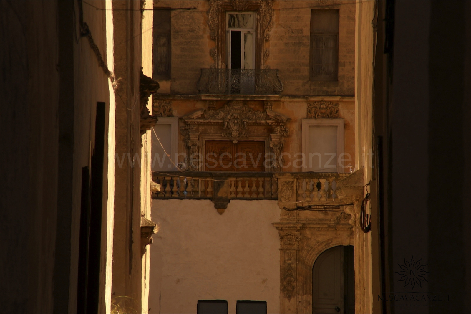 Vicolo del centro storico barocco di Lecce con balconi e portali scolpiti in pietra leccese dorata
